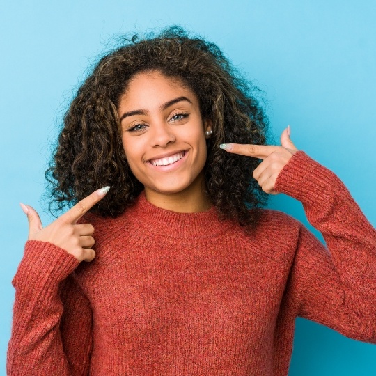 Teenage girl pointing to her smile