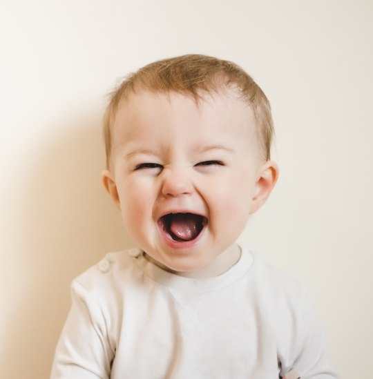 Toddler laughing with their mouth wide open