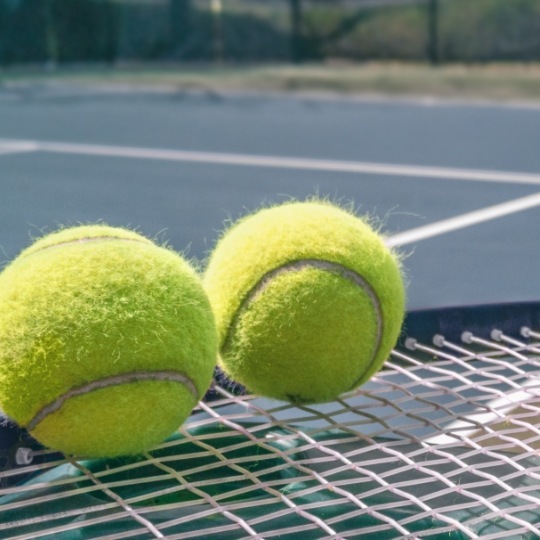 Close up of two tennis balls sitting on racket