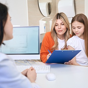 a parent filling out patient forms for their child to see a pediatric dentist