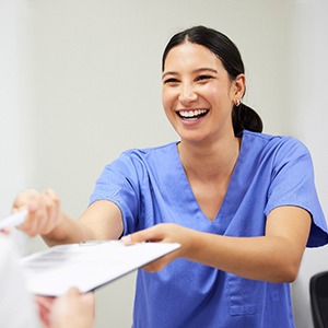 a dental assistant handing a patient forms