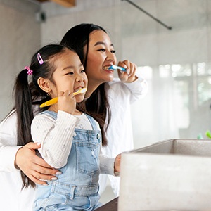 a mom and daughter brushing their teeth together