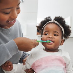 A mom brushing her child’s teeth