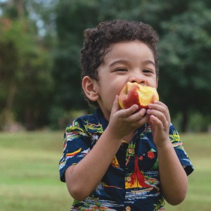 A child eating a peach outside