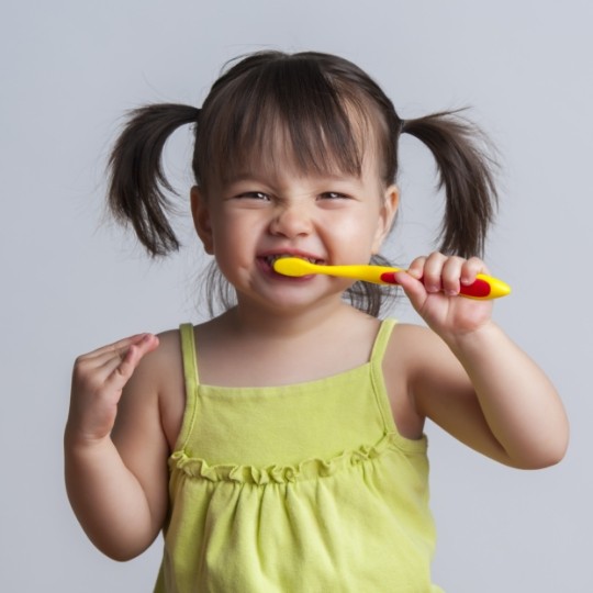 Young girl with pigtails brushing her teeth