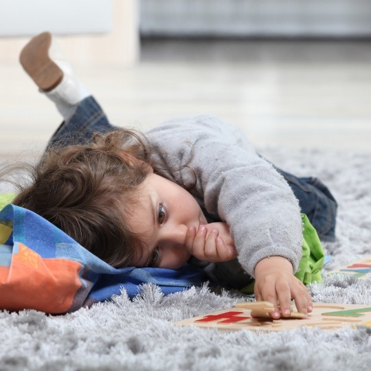 Young child laying on floor and sucking their thumb