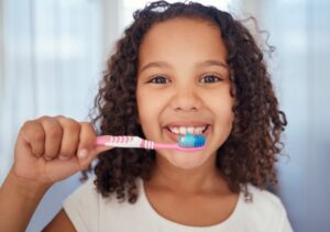 a child holding a toothbrush up to their mouth
