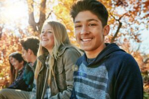 teens sitting on a bench together and smiling